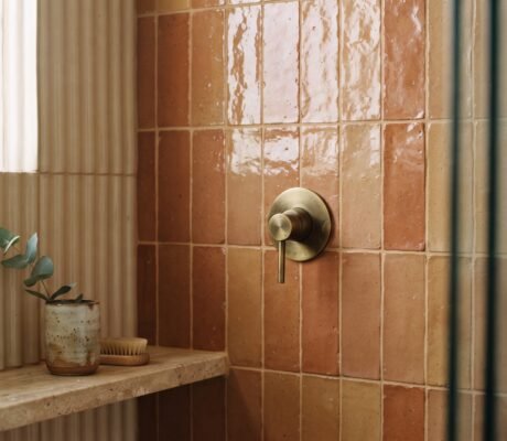 Handmade zellige shower tile in warm clay glaze with stacked vertical layout and brass fixture — bathroom tile trends 2026