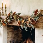 Finished DIY fall garland of dried eucalyptus, oak leaves, wheat and orange slices draped on an oak mantel