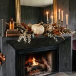 Elegant Halloween mantel decor with an asymmetric dried garland, brass candlesticks with cream tapers and a pale heirloom pumpkin